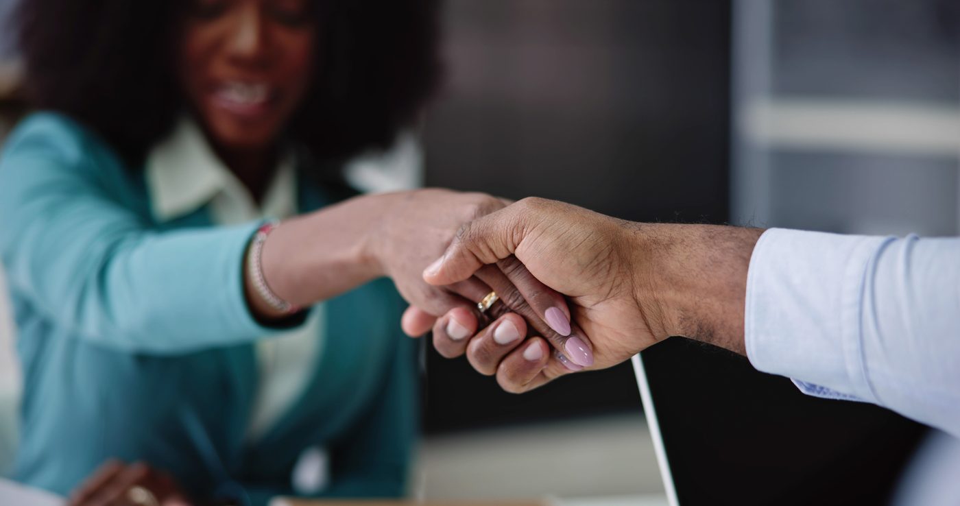 Two partners shaking hands over a shared project